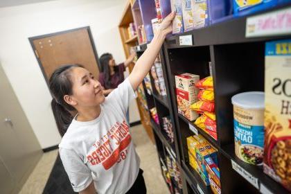 A student restocks shelves at the Pacific Food Pantry